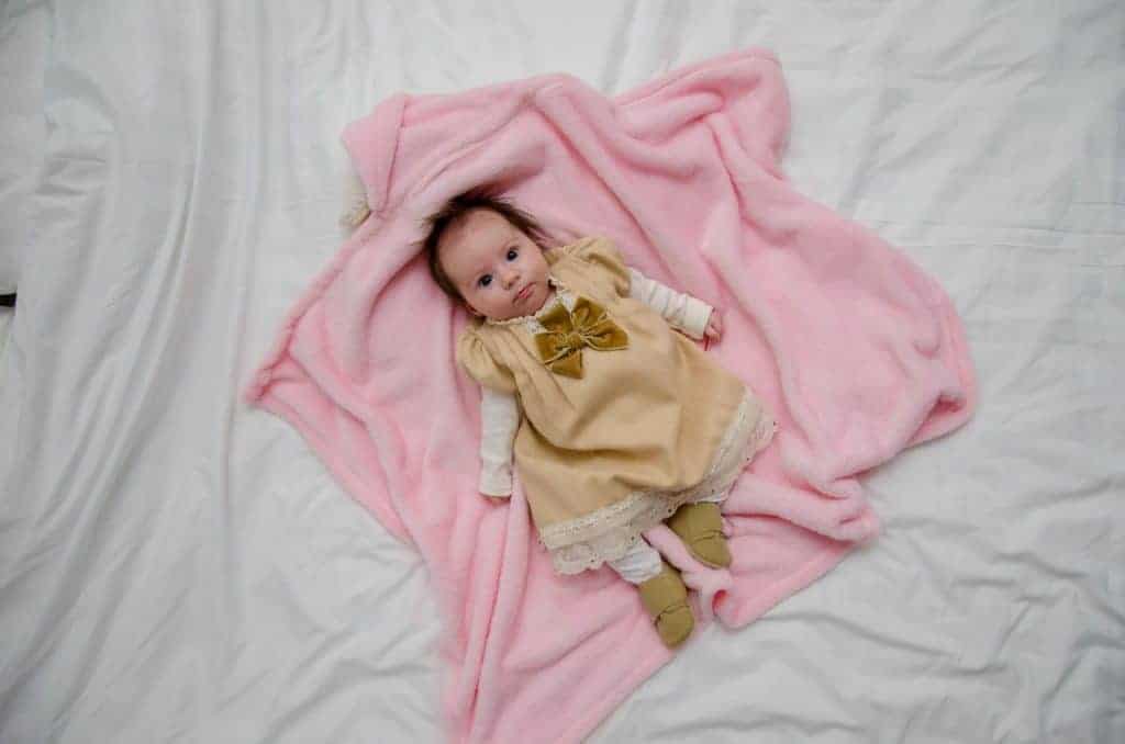 baby girl lying down on pink blanket