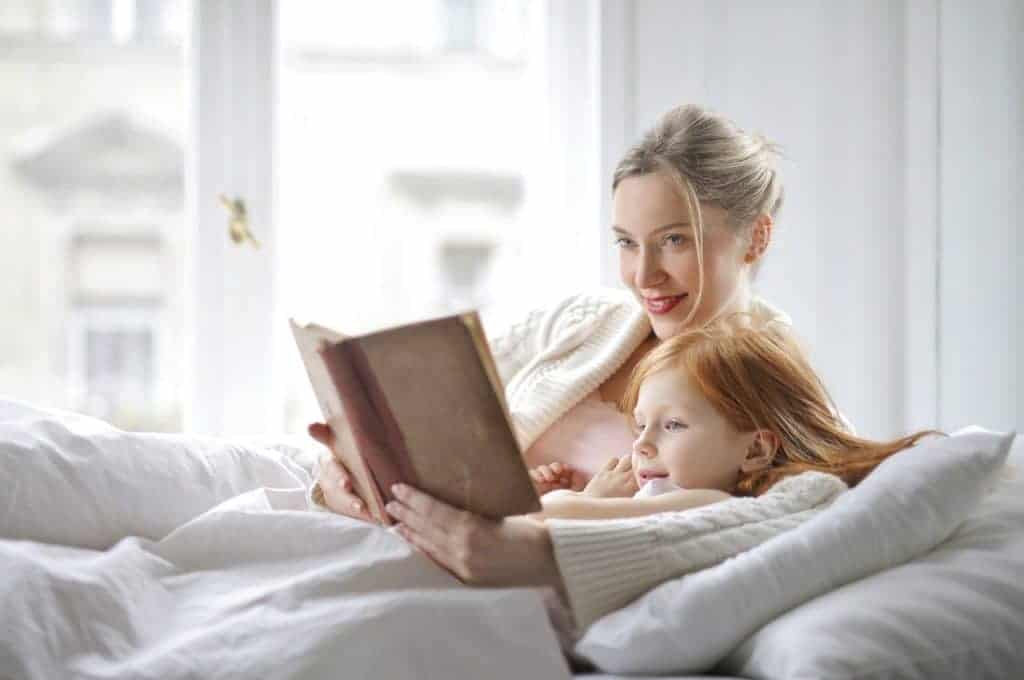 Mother and child reading a book on bed