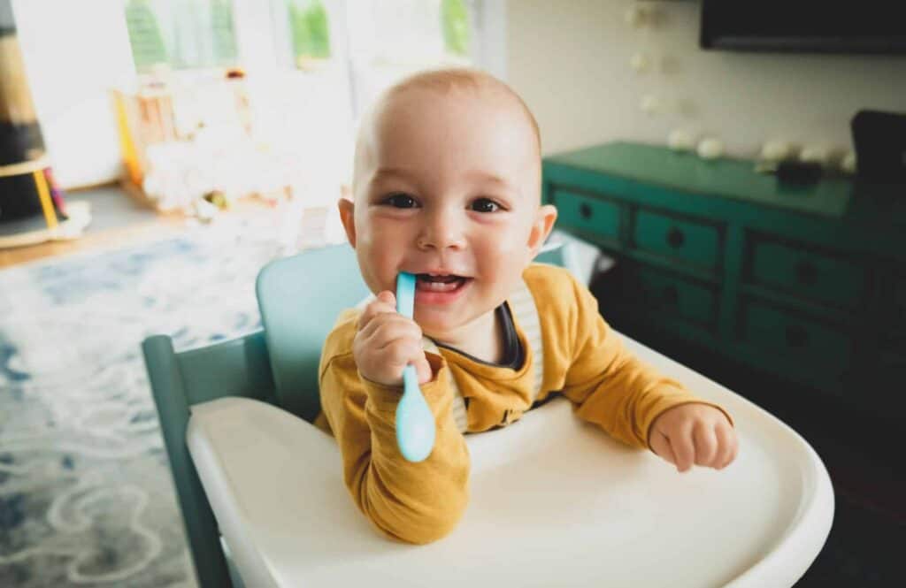 Baby holding spoon in mouth