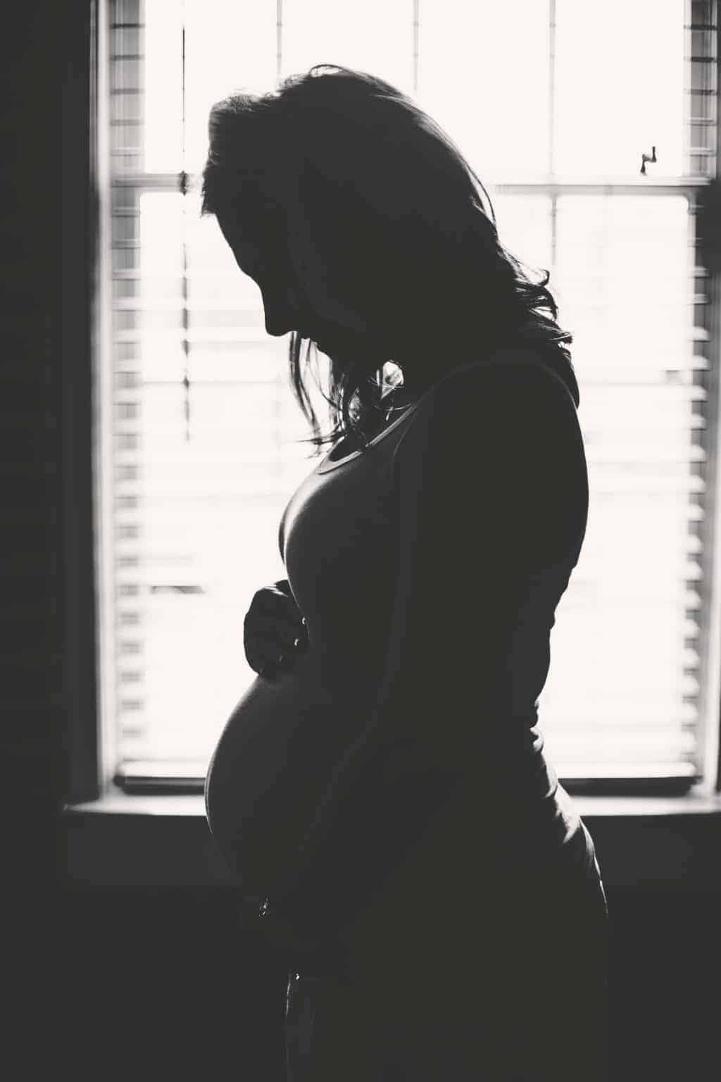 Pregnant Women standing behind the window