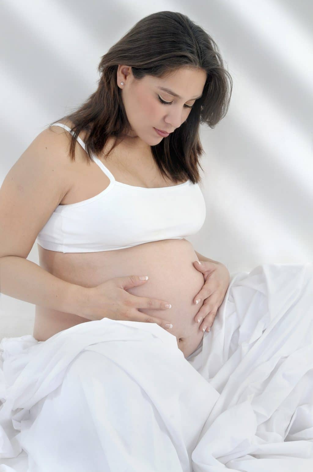 Pregnant Women wearing a maternity bra is seating at her bed