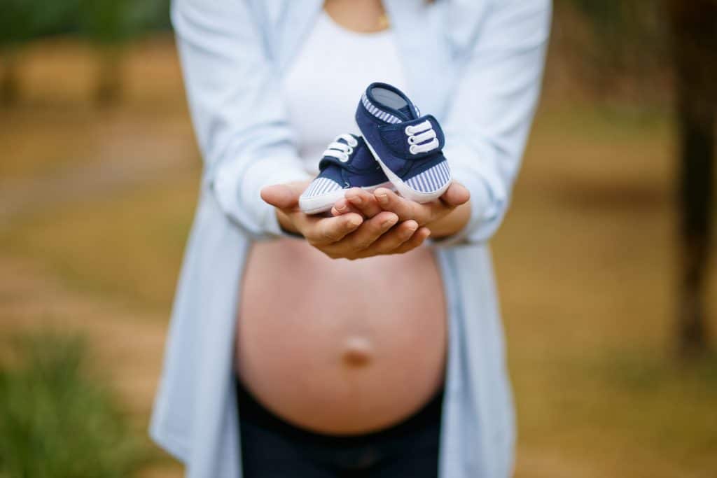 Pregnant woman holding a baby's shoes