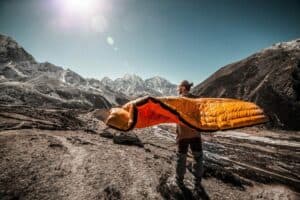 man carrying sleeping bag in the moutain