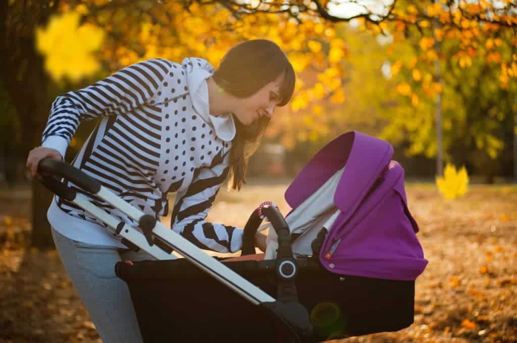 woman looking her baby in the stroller