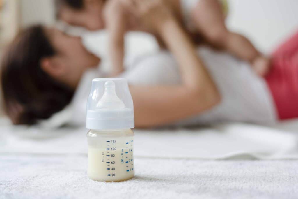 Baby formula with mom and baby in the background