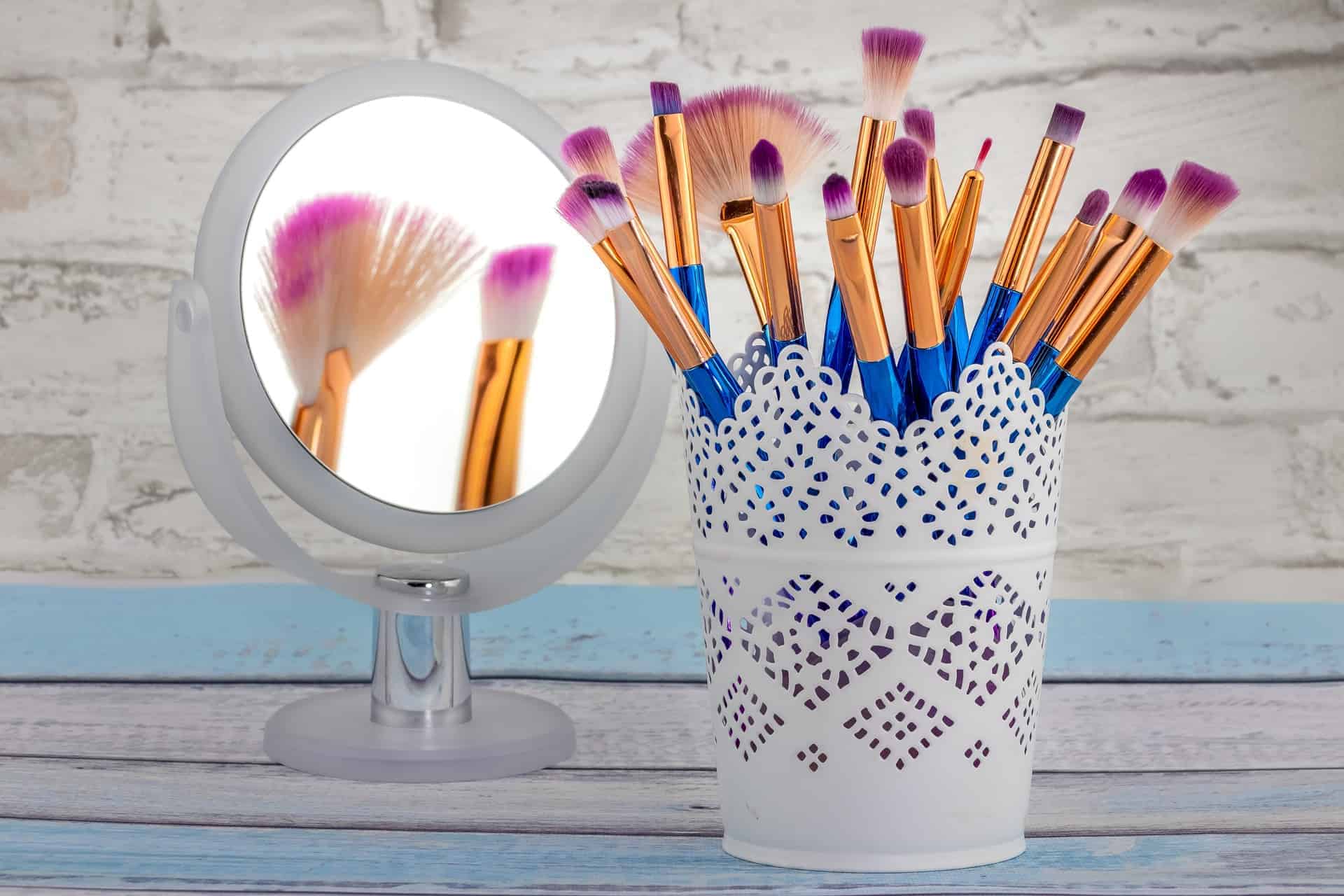 Makeup brushes in a cup beside one of the best lighted make up mirrors
