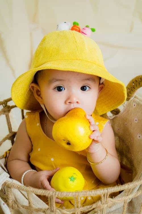 baby holding ripe pear