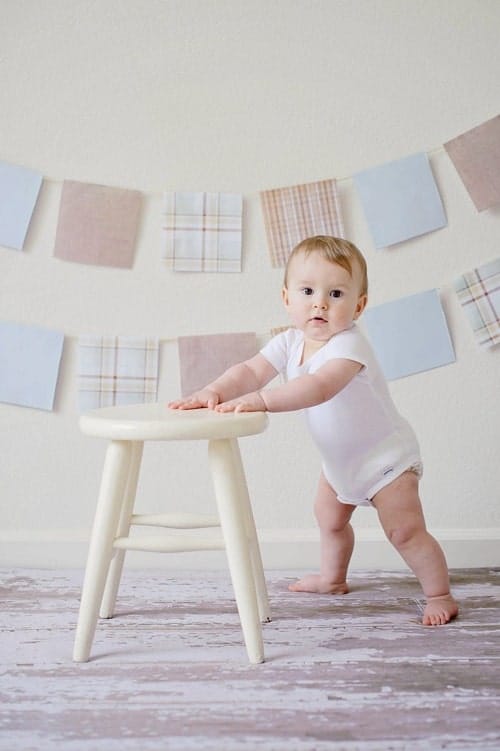baby standing beside stool