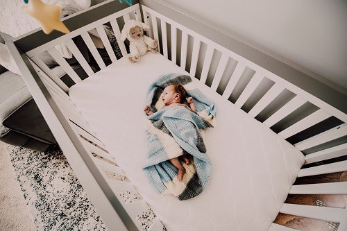 baby inside crib with blue blanket