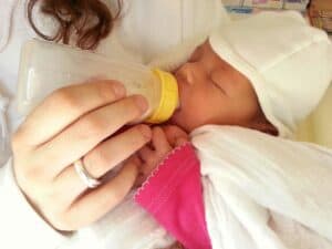 A tiny baby is being bottle fed with milk that was saved in breast milk storage bags