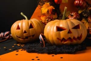 carved jack o lanterns sitting on an orange table cloth as Halloween Classroom Decorations